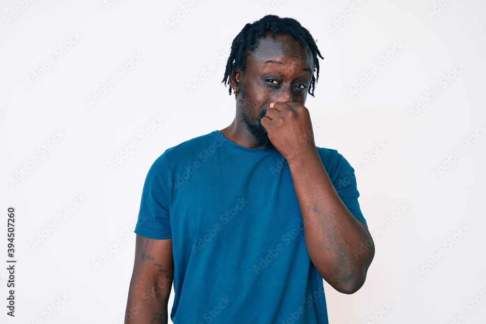 Sticker young african american man with braids wearing casual clothes smelling something stinky and disgusti