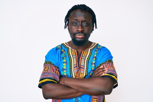 Young african american man with braids wearing traditional africa tshirt skeptic and nervous, disapproving expression on face with crossed arms. negative person.