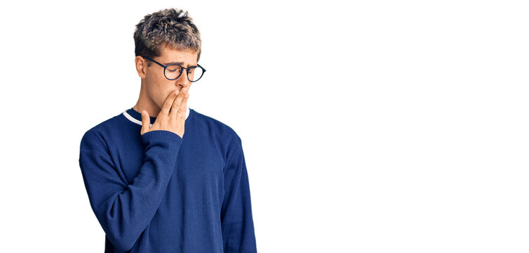 Young handsome man wearing casual clothes and glasses bored yawning tired covering mouth with hand. restless and sleepiness.