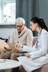 Obraz premium Young pretty brunette doctor pointing at paper with medical recommendations