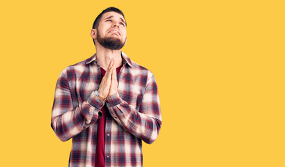 Young handsome man wearing casual shirt begging and praying with hands together with hope expression on face very emotional and worried. begging.
