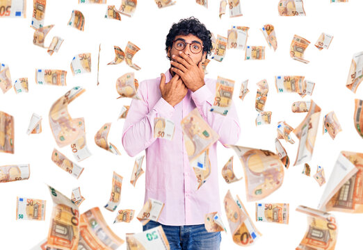 Handsome young man with curly hair and bear wearing business clothes shocked covering mouth with hands for mistake. secret concept.