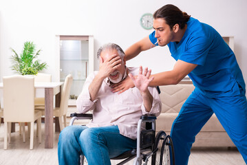 Old man in wheel-chair and young bad caregiver indoors