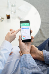 Hands of young female doctor in whitecoat pointing at display of smartphone