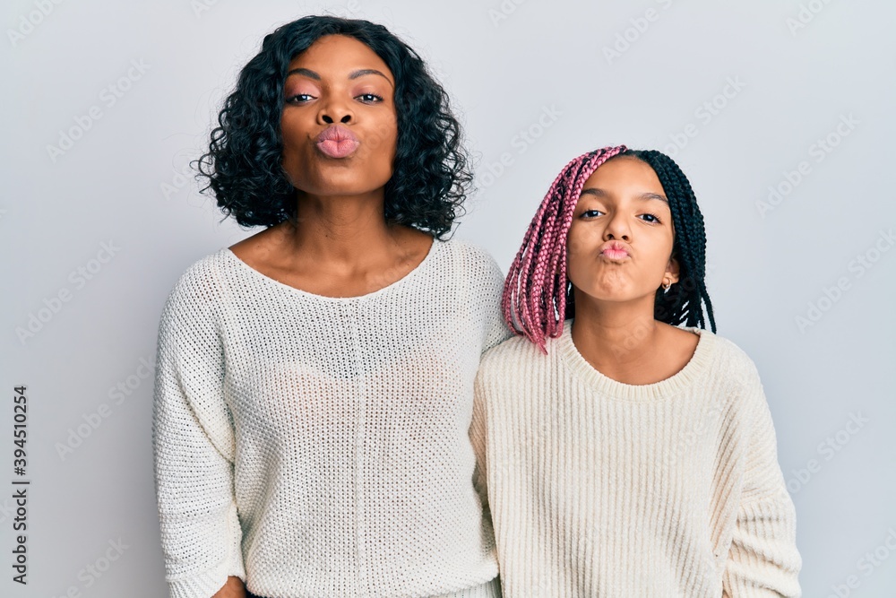 Sticker Beautiful african american mother and daughter wearing casual clothes and hugging looking at the camera blowing a kiss on air being lovely and sexy. love expression.