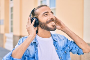 Young middle eastern man smiling happy using headphones at the city.