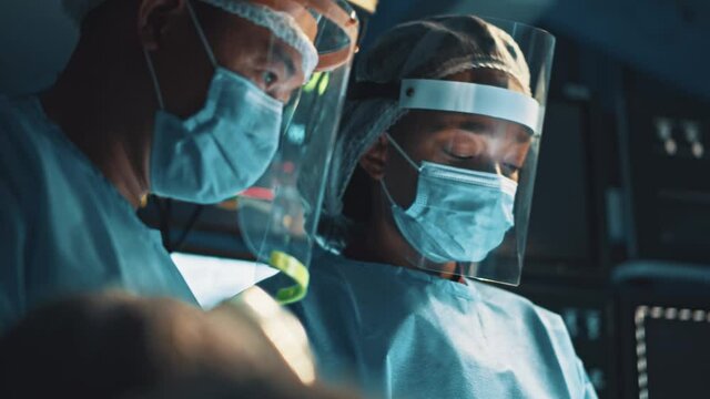 Diverse medical couple of surgeon and nurse performing medical operation on infected patient at hospital room. Cooperation. Surgical staff.