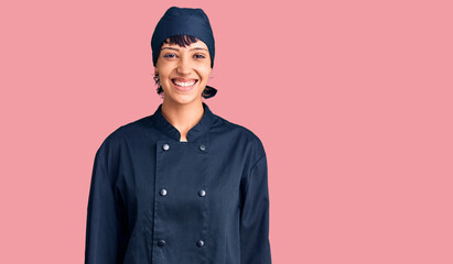 Young brunette woman with short hair wearing professional cook uniform with a happy and cool smile...