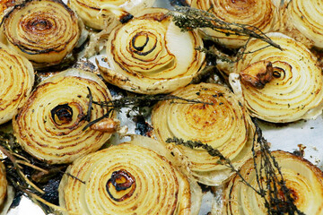 grilled caramalized half white onions with herbs on a metal tray