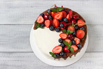 Delicious cake with fresh berries, fruits and chocolate ganache.
