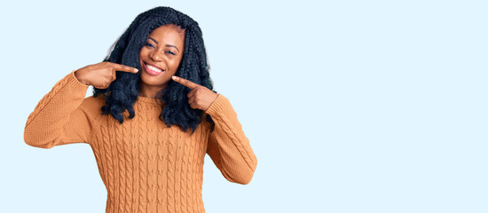 Beautiful african american woman wearing casual  sweater smiling cheerful showing and pointing with fingers teeth and mouth. dental health concept.