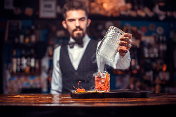 Portrait of mixologist pouring fresh alcoholic drink into the glasses
