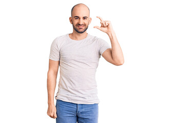 Fototapeta premium Young handsome man wearing casual t shirt smiling and confident gesturing with hand doing small size sign with fingers looking and the camera. measure concept.