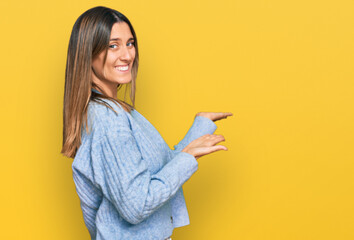 Young woman wearing casual clothes pointing aside with hands open palms showing copy space, presenting advertisement smiling excited happy