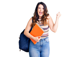 Beautiful young brunette woman wearing student backpack hodling books screaming proud, celebrating victory and success very excited with raised arms