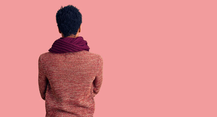 Young african american man wearing casual winter sweater and scarf standing backwards looking away with crossed arms