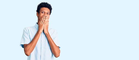 Young african american man wearing casual clothes laughing and embarrassed giggle covering mouth...