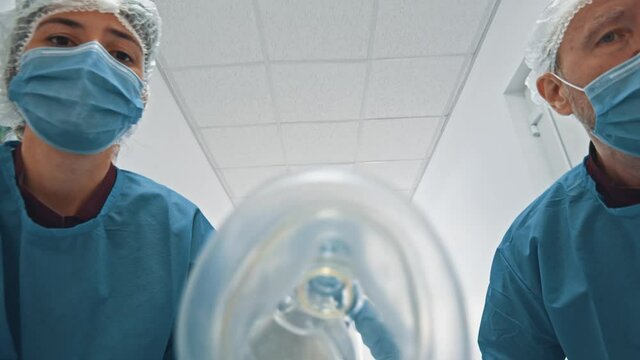 POV shot of patient lying on stretcher bed seeing group of paramedic doctors running through hospital corridor for emergency surgery.