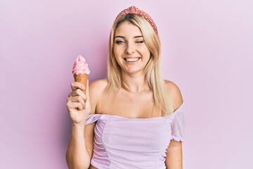 Young caucasian woman holding ice cream winking looking at the camera with sexy expression,...