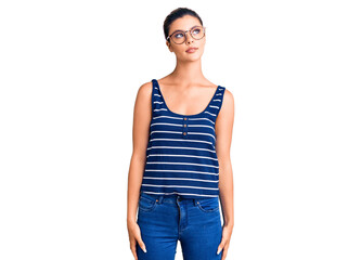 Fototapeta premium Young beautiful woman wearing casual clothes and glasses smiling looking to the side and staring away thinking.