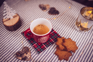 table decorated with cinnamon and ginger cookies, Christmas lights, other Christmas items and a cup of hot coffee