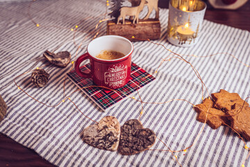 table decorated with cinnamon and ginger cookies, Christmas lights, other Christmas items and a cup of hot coffee