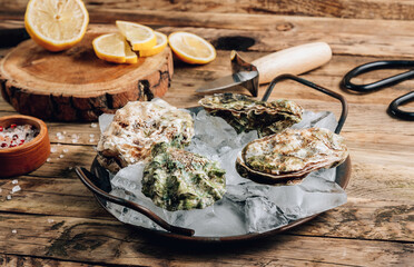 Fresh oysters with ice and lemon on a rustic wooden background.