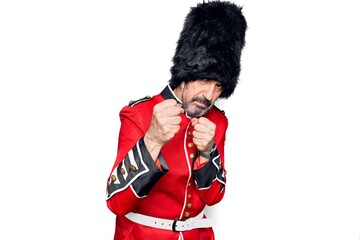 Middle age handsome wales guard man wearing traditional uniform over white background Ready to fight with fist defense gesture, angry and upset face, afraid of problem