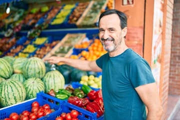Middle age man with beard smiling happy shopping vegetables at the grocery supermarket