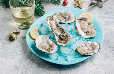 Oysters with lemon, ice and white wine on concrete background with a festive decor.