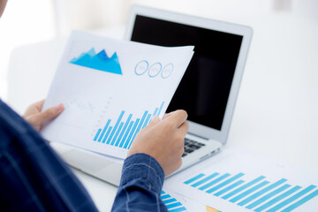 Hand of young business man looking document data graph and chart paper, marketing and investment, report of statistics profit for financial, economic and growth of finance, management and planning.