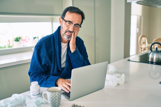 Middle age man feeling sick with cold and fever at home, ill with flu disease working from home
