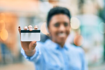 Young african american girl smiling happy holding credit card at the city.