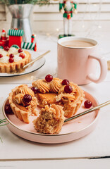 Mini cheesecake with cranberries on a white wooden table with Christmas decorations.