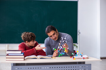 Young male teacher and schoolboy in the classroom