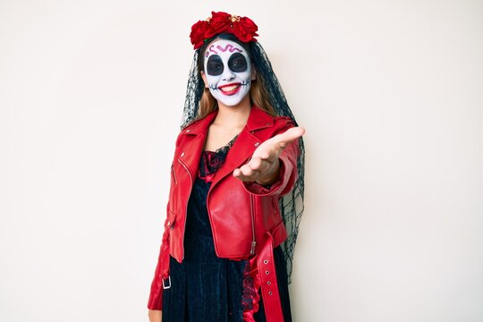 Woman wearing day of the dead costume over white smiling cheerful offering palm hand giving assistance and acceptance.