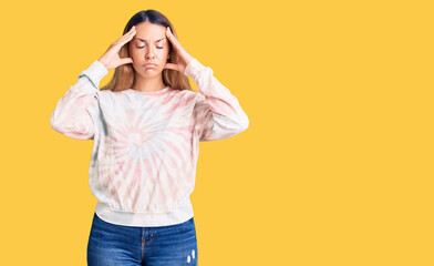Beautiful young woman wearing casual tie dye sweatshirt suffering from headache desperate and stressed because pain and migraine. hands on head.