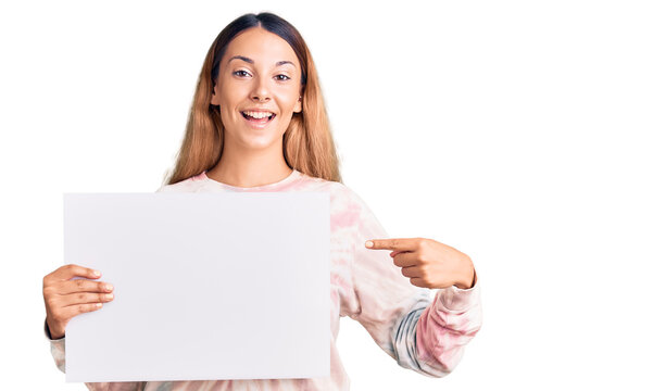Beautiful young woman holding blank empty banner smiling happy pointing with hand and finger