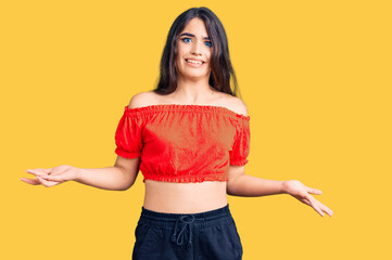 Brunette teenager girl wearing casual clothes clueless and confused expression with arms and hands...