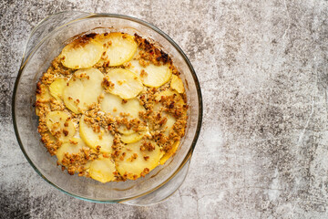 Close up on moussaka greek traditional meal with potatoes and meat in the glass pot on marble table with copy space