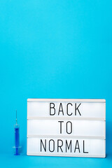 Back to normal concept - title board on the blue background with syringe vaccine injection abstract...