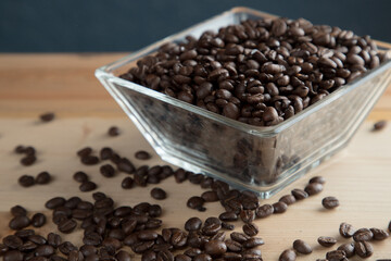 Café negro en grano sobre madera y en un recipiente de cristal 