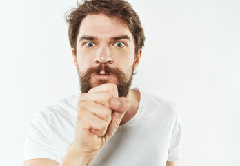 Naklejka premium Emotional man on a white background in a T-shirt shows a gesture with his hands