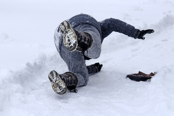 Eine Frau rutscht auf einem schneebedeckten Gehweg aus
