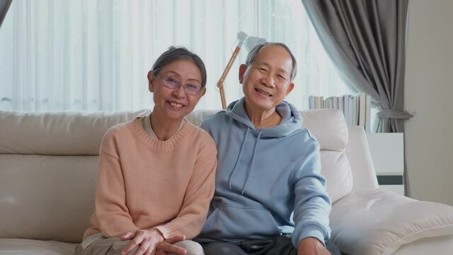 Portrait of Asian seniour couple sitting and kissing in living room.