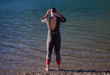 authentic triathlon athlete getting ready for swimming training on lake