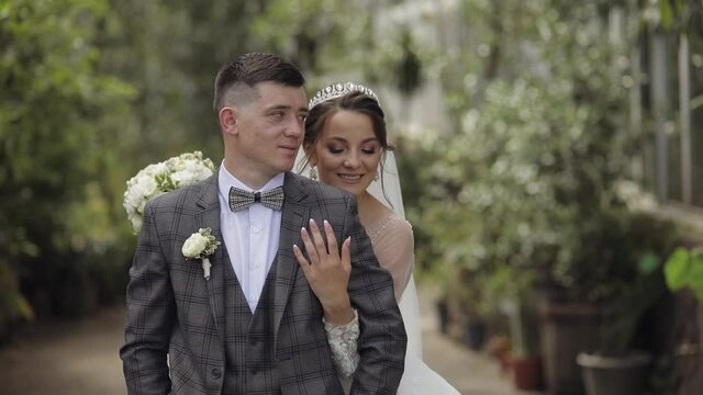 Newlyweds. Lovely caucasian bride and groom walking in park. Embracing, hugs. Happy wedding couple family. Man and woman in love. Bride in gorgeous wedding dress. Bridegroom in jacket. Slow motion