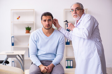 Young sick man visiting old doctor otolaryngologist