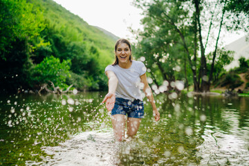 The young woman at a tropical river playful, the splashing of water. Skincare spa treatment concept. Summer vacation. Healthy happiness lifestyle.Enjoying spring/summer nature