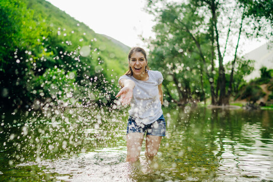 The young woman at a tropical river playful, the splashing of water. Skincare spa treatment concept. Summer vacation. Healthy happiness lifestyle.Enjoying spring/summer nature